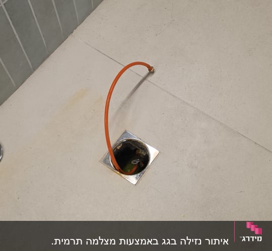 צינור כתום יוצא מרצפת חדר אמבטיה
